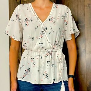 Feminine floral blouse with a tie around the waist.